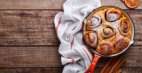 Cinnabon cinnamon rolls buns with pumpkin, nut, caramel and sugar cream iced on rustic wooden background table. Top view. Sweet Homemade Pastry christmas baking. Kanelbule - swedish dessert.