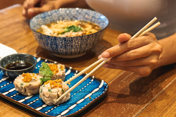 Close up of hand of woman eating asian food with chop sticks