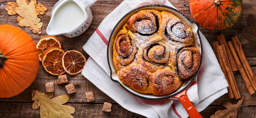 Cinnabon cinnamon rolls buns with pumpkin, nut, caramel and sugar cream iced on rustic wooden background table. Top view. Sweet Homemade Pastry christmas baking. Kanelbule - swedish dessert.