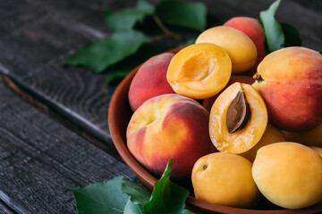 Composition of pineapple variety apricot and peaches in a clay plate on dark wooden background. Top...