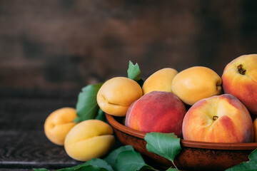 Several peaches and an apricot close-up in plate on wooden background. Bright, juicy healthy fruits