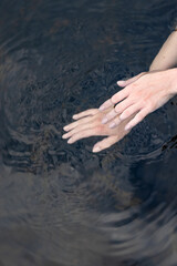 woman's hand gently touches the water in the pond, a close horizontal photo on the theme of tranquility