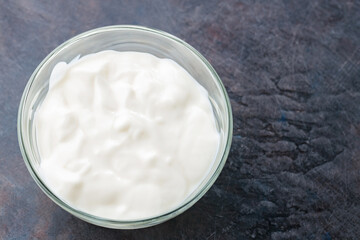 Fototapeta na wymiar Yogurt in a bowl. Greek yogurt on a dark background. Dairy product for a healthy breakfast. Top view. Copy space