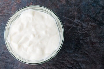 Yogurt in a bowl. Greek yogurt on a dark background. Dairy product for a healthy breakfast. Top view. Copy space