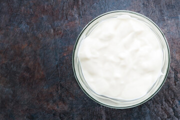 Yogurt in a bowl. Greek yogurt on a dark background. Dairy product for a healthy breakfast. Top view. Copy space