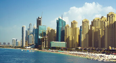 City of skyscrapers, Dubai marina in the sunny day with front line of beach hotels and blue water of Persian gulf. 