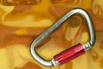 Large, versatile D-shaped grey aluminum auto-locking carabiner for rock climbing on a fingerboard