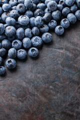 Blueberries scattered on a dark background. Ripe blueberries for a healthy breakfast. Concept seasonal berries. Healthy vegetarian food. Top view. Copy space