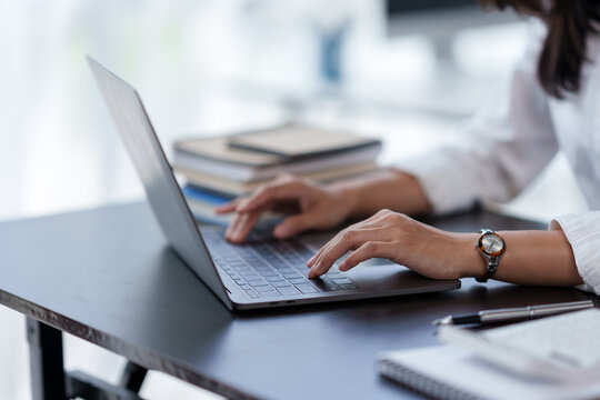 Close-up of a business woman typing a laptop computer on a desk in the office.