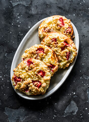 Puff pastry buns with ricotta, strawberries and crumble on a dark background, top view