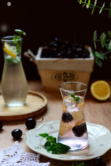 mojito cocktail on a wooden table, lemon , and mint lemonade sit on the wooden dining table. Cold, refreshing summer lemonade or mojito With fruits cherries .