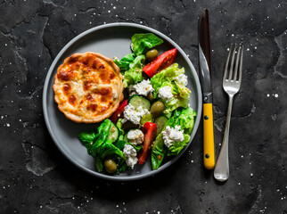 Delicious lunch - mini canned tuna, mozzarella quiche and greek salad on a dark background, top view