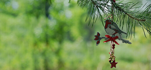 New Year's toy bird bullfinch made of wood with bells hangs on a pine branch on a green background....