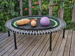 mini trampoline with wooden Indian clubs and a slam ball for fitness exercising and rebounding in a...