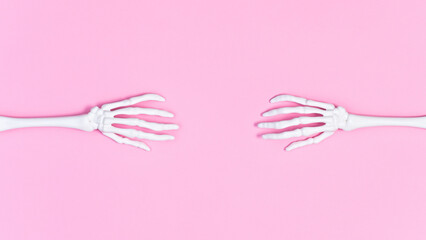 Creepy skeleton hands on pastel pink background. Flat lay copy space. Halloween concept