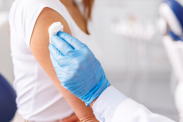 General practitioner disinfecting patient vaccine application spot