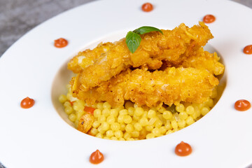 Recipe for chicken tenders with corn flakes and Italian Piombo pasta risotto and peppers. High quality photo