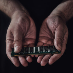 Man hands hold a green computer board with a ram memory on a black background