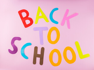 Inscription Back to school with colored letters on a pink background. Back to school concept