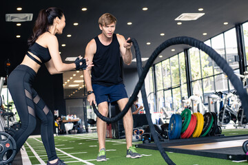 Young man doing crossfit exercise in battle ropes session.