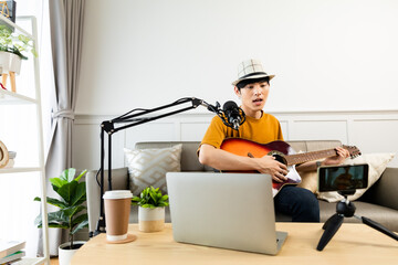 Asian guitarist livestream virtual video tutorial at home,artist musician blogger sit on sofa in...