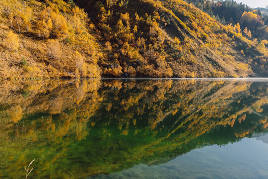 Mountain lake with reflection on surface, autumnal trees