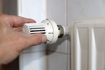 Gas shortage and rising heating costs: hand on a radiator thermostat