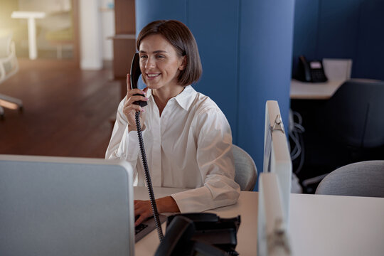 Bussy Woman Worker Talk Phone With Client Sit On Her Workplace In Office. Blurred Background