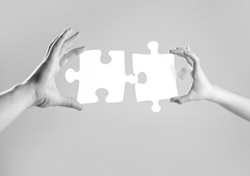 Hands connecting puzzle. Puzzles. Hand of the child and hand of mother fold puzzle, closeup. Hands hold puzzles. Solution of problems
