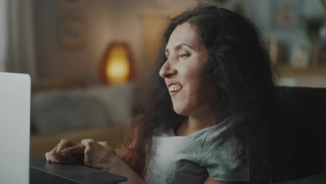 Happy woman with a physical disability in a wheelchair smiling and laughing while having a video call conference on laptop