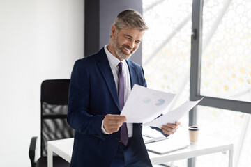 Fototapeta premium Successful Entrepreneurship Concept. Happy Mature Businessman In Suit Checking Financial Papers