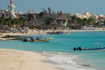 View of the waterfront in Playa del Carmen, Mexico, with the lighthouse and fishing boats near the beach