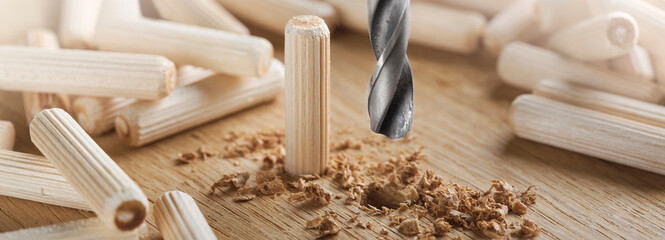 drill bit makes hole in wooden oak board for wooden dowel. - obrazy, fototapety, plakaty