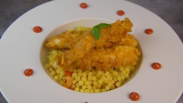 Recipe for chicken tenders with corn flakes and Italian Piombo pasta risotto and peppers on turntable. High quality video