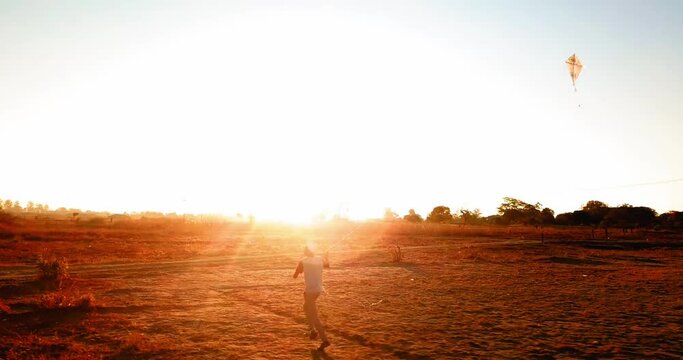 Panning Shot Of Man Flying Kite And Running In Field During Sunset - Lusaka, Zambia