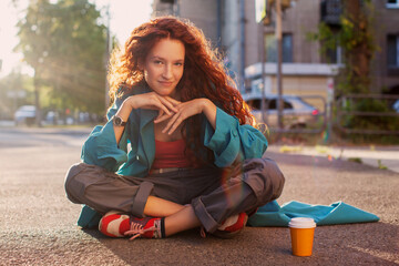 Young red haired woman walking on the street in city