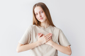 hopeful young woman holding hands on chest