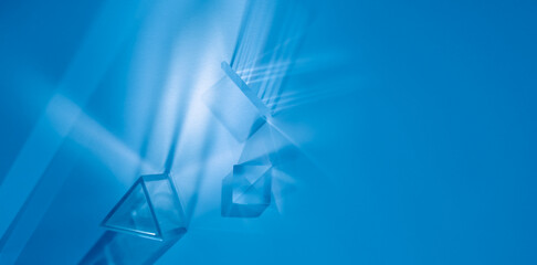 Glass prisms and cubes with spectrum rays. Abstract blue background with reflection and refraction...