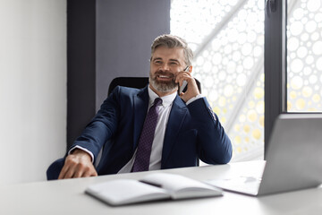 Phone Call. Smiling Mature Businessman In Suit Talking On Cellphone At Workplace