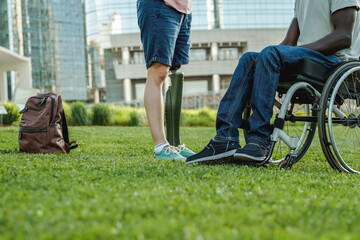 Obraz premium Diverse friends with physical disability having fun outdoor at city park - Focus on African man on wheelchair