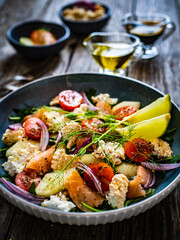 Salmon salad - smoked salmon, white smoked cheese and fresh vegetables on wooden table
