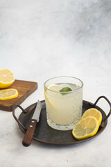 A glass of lemonade with lemon on a gray background.