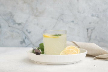 A glass of lemonade with lemon on a gray background.