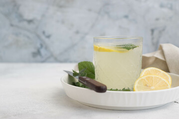 A glass of lemonade with lemon on a gray background.