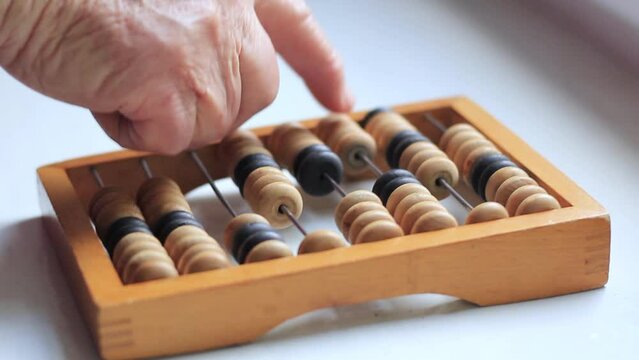 Elderly woman's hand counts on vintage abacus