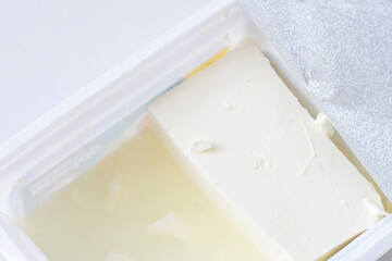 white cheese in an open package close-up on a white background
