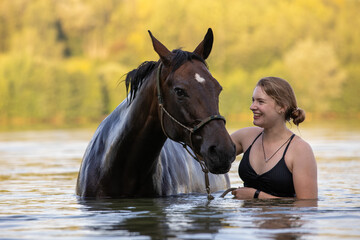 Junge Frau mit Pferd im See