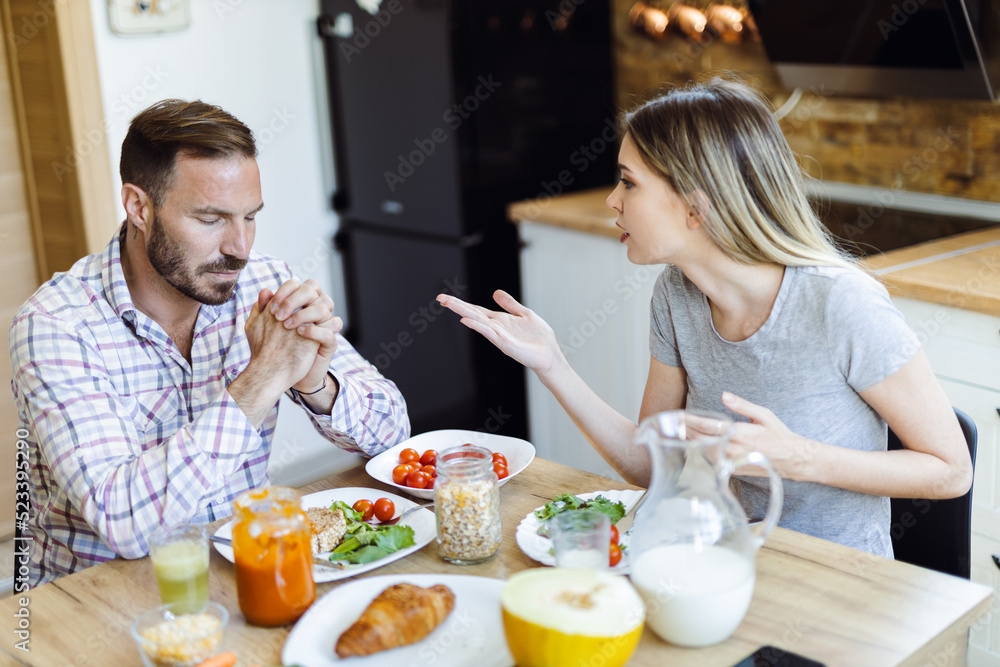 Wall mural Frustrated young couple arguing during breakfast time at home