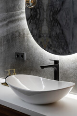 white washbasin, modern black faucet and mirror in washroom