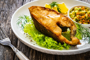 Fish dish - fried halibut with French fries and lemon on wooden table
